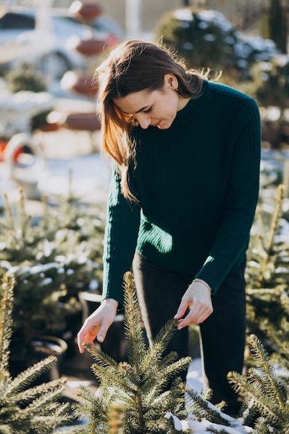 young-woman-choosing-christmas-tree-greenhouse_1303-19409-1195621