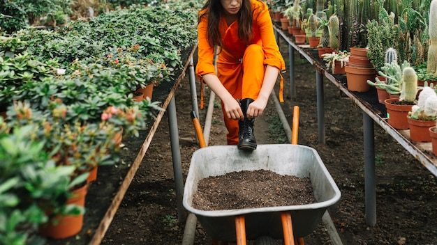 female-gardener-tying-wellington-boot-greenhouse_23-2147918498-5787997