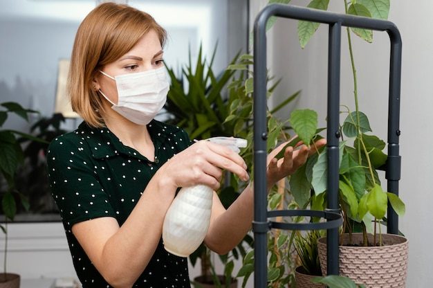 medium-shot-woman-with-mask-watering-plant_23-2148826043-7083346