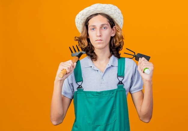 young-gardener-man-wearing-jumpsuit-hat-holding-mini-rake-mattock-with-serious-face_141793-46974-6731232